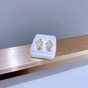 Detailansicht der goldenen Blumenohrringe mit weißen Kristallen auf einem Metallständer