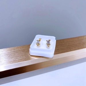 Makro-Detail der goldenen Titanstahl-Ohrstecker mit funkelndem Zirkonia-Blumendesign