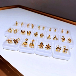 Set aus vergoldeten Titanstahl-Ohrsteckern mit glitzernden Zirkonia-Formen in Boxen