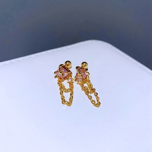 Makroaufnahme goldener Ketten-Ohrringe mit quadratischen rosa Zirkon-Steinen