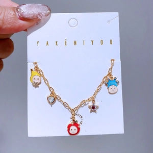 Detailaufnahme eines vergoldeten Bettelarmbands mit Emaille-Cartoons und glitzernden Steinen