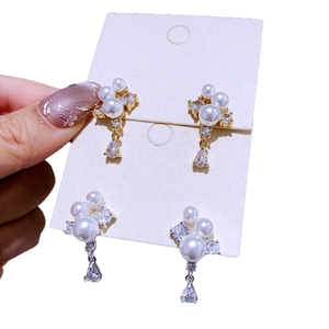 Elegante goldene und silberne Tropfenohrringe mit Zirkonia und Perlen auf einer Displaykarte