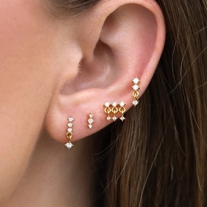 Nahaufnahme des vergoldeten Zirkon-Ohrring-Sets mit mehreren Piercings am Ohr