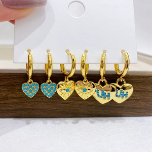 Detailed macro view of three pairs of gold-plated heart charms with blue zircon inlay