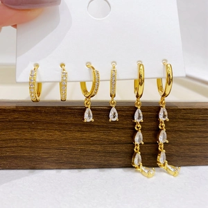 Detailed set of three gold-plated earrings with cubic zirconia charms on display