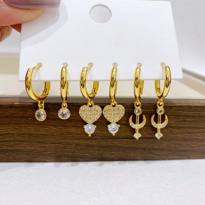 Detailed view of three pairs of gold-plated earrings with zircon hearts and stars