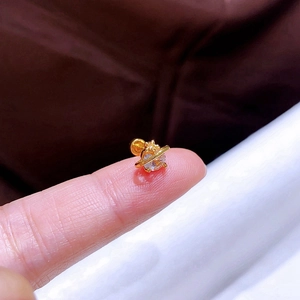 Goldener Planetenohrstecker mit Kristall und Schraubverschluss auf einer Fingerspitze