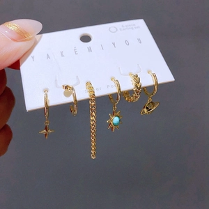 Gros plan d'un lot de 6 boucles d'oreilles dorées avec breloques soleil et étoile turquoise