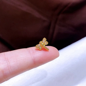 Detailansicht eines kleinen Gold-Libellen-Ohrsteckers mit Kristallen auf einer Fingerspitze