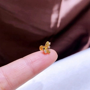 Detail eines zierlichen Schmetterlings-Ohrsteckers aus Gold mit Zirkonia am Finger