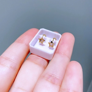 Nahaufnahme minimalistischer goldener Stern-Ohrstecker in weißer Box in der Hand
