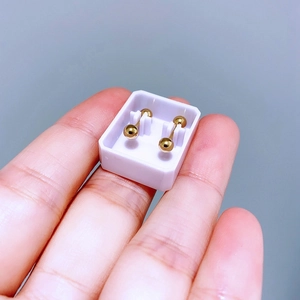 Makroaufnahme von kleinen goldenen Kugelohrringen auf der Hand mit poliertem Metall-Finish