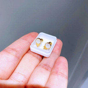 Nahaufnahme von 18K vergoldeten Schraubohrsteckern mit weißem Emaille-Inlay im Kreis