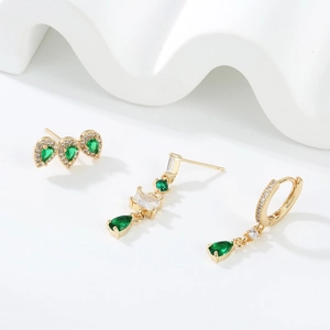 Detail view of gold earrings set featuring emerald green zircons and water drop crystals