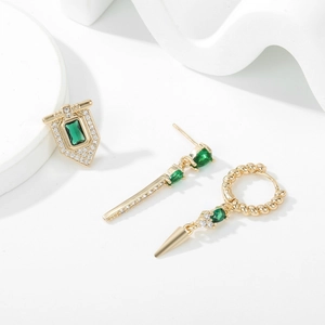 Close-up of gold earrings set with emerald green stones and diamond accents