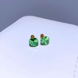 Makroaufnahme quadratischer grüner Zirkon-Ohrstecker auf einem weißen Lederdisplay