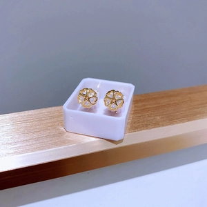Detailaufnahme goldener Blumenohrstecker mit Kristallen in einer Präsentationsbox