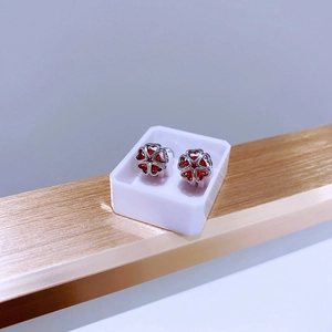 Detailaufnahme der silbernen Blumenohrringe mit roten Herzsteinen in einem Schaukasten