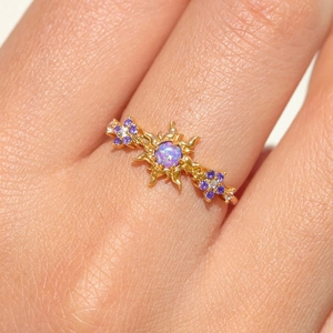 Nahaufnahme eines vergoldeten Sonnenrings mit lila Opal und violetten Diamant-Blumendetails
