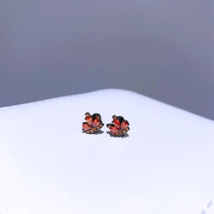 Makrofoto von schwarzen Schmetterling-Ohrsteckern mit roten und orangen Zirkonia-Steinen
