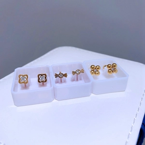 Drei Paar goldene Titan-Ohrstecker mit Kleeblatt und Kristallen in einer Geschenkbox