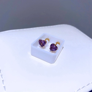 Makroansicht von lila Herz-Zirkonia-Ohrringen mit Goldbeschichtung in weißer Geschenkbox