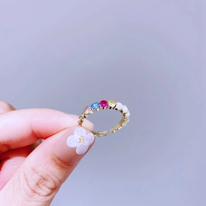 Detailansicht eines goldenen Herz-Rings mit bunten Edelsteinen und Perlen