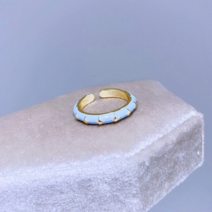Dettaglio macro dell'anello in smalto azzurro con stelle dorate su velluto champagne