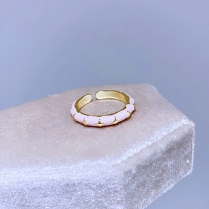 Dettaglio dell'anello regolabile in smalto rosa con stelle dorate su supporto in velluto