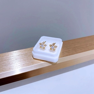 Gros plan de boucles d'oreilles flocon dorées avec oxydes de zirconium sur support