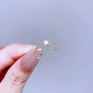 Detail eines offenen Stern-Mond-Rings mit weißem Opal-Inlay am Finger getragen