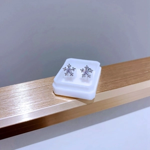 Détail macro de boucles d'oreilles flocon de neige avec zircons dans un écrin blanc