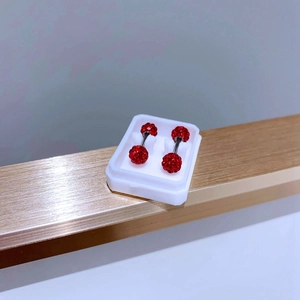 Macro shot of 5mm red pavé crystal ball barbell earrings in a white jewelry box