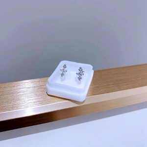 Gros plan de boucles d'oreilles croix avec zircone sur un support à bijoux en acier