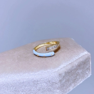 Dettaglio di un anello a fascia dorato con smalto azzurro e cristalli di zircone