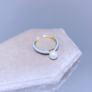 Dettaglio anello in smalto azzurro con perla bianca su fascia dorata regolabile