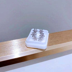 Gros plan de boucles d'oreilles en titane avec trois fleurs en zircon sur un présentoir
