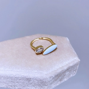 Dettaglio anello dorato aperto con zircone ovale e pietra azzurra su supporto in velluto