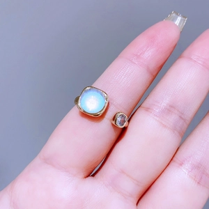 Dettaglio anello dorato regolabile con pietra di luna blu chiaro e pietra di zircone
