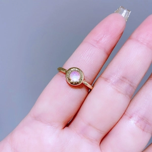 Dettaglio ravvicinato di un anello d'oro con pietra di luna rosa e trame ornate