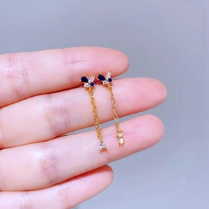 Detailaufnahme eines Schmetterling-Ohrrings mit blauen Zirkonia und goldenen Quasten