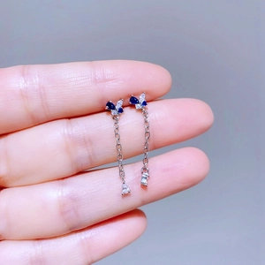 Nahaufnahme asymmetrischer Schmetterlings-Ohrringe mit blauen Zirkon-Steinen aus Silbermetall