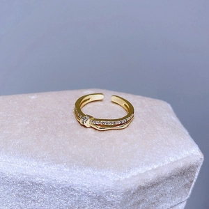 Dettaglio macro di un anello intrecciato placcato oro con zirconi bianchi su velluto