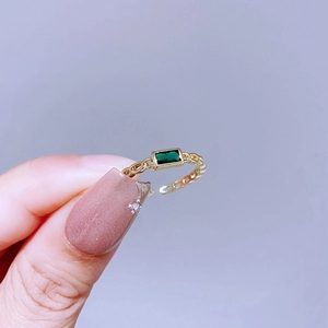 Detail eines grünen Edelsteinrings mit goldener Panzerkette und verstellbarem Design