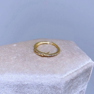 Dettaglio dell'anello a nodo dorato con diamanti su espositore in velluto rosa