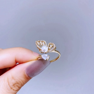 Close-up of golden butterfly ring with pearls and pear-shaped stone on a hand