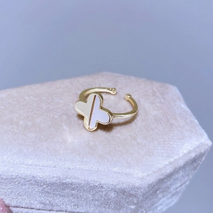 Elegante anello a quadrifoglio dorato con smalto bianco su portagioie in velluto viola