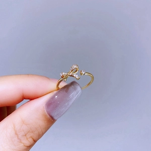 Detail of a golden bow ring featuring sparkling zircons and an adjustable open band