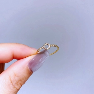 Detail of a thin gold ring with a hollow circle centerpiece and sparkling zircon stones