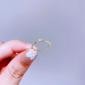 Nahaufnahme eines eleganten goldenen Rings mit Zirkon-Edelstein und floraler Nagelkunst